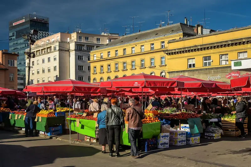Bancarelle di frutta e verdura sotto gli ombrelloni rossi del mercato Dolac a Zagabria